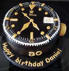 a black and gold birthday cake with a watch on it