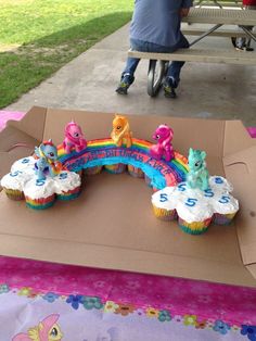 there are cupcakes in the shape of a rainbow on top of a box