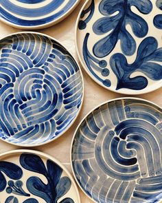 four blue and white plates with designs on them