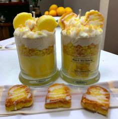 two desserts are sitting on a table with lemon slices and marshmallows