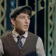 a young man wearing a hat and vest