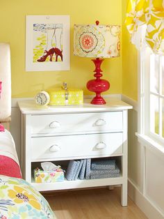 a bedroom with yellow walls, white furniture and colorful accessories on the nightstands in front of the bed