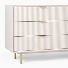 a white chest of drawers with gold handles