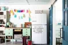 a room with a refrigerator, desk and shelves