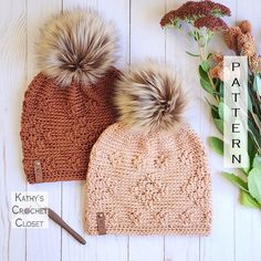 two knitted hats with pom - poms sitting next to each other on a white wooden surface