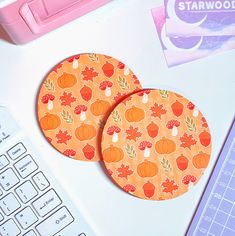 two coasters sitting on top of a white desk next to a keyboard and mouse