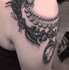 the back of a woman's shoulder with a clock and flowers tattoo on it