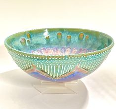 a blue and green bowl sitting on top of a white tablecloth covered countertop