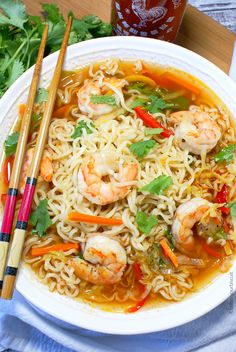 shrimp and noodle soup with chopsticks on a white plate next to a jar of ketchup