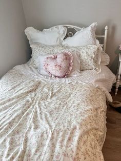 a white bed topped with lots of pillows next to a night stand and nightstands