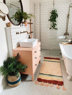 a bath room with a tub a sink and a rug on the floor in front of a mirror