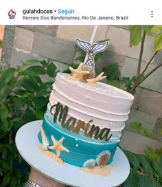 a person holding up a cake decorated with the word mamma and starfish on it