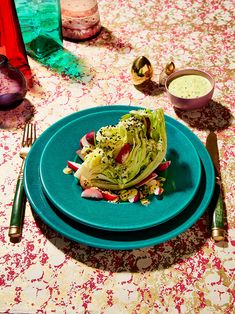 a blue plate topped with lettuce on top of a table next to silverware