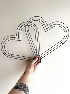 a hand holding a piece of paper with two hearts drawn on the wall behind it