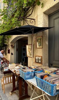 a man standing next to a table filled with lots of books under an open umbrella