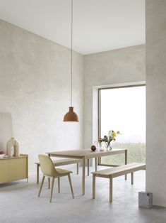 a dining table with two chairs and a bench in front of a window that looks out onto the countryside