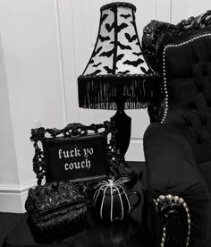 a black and white photo of a couch, table with halloween decorations on it next to a lamp