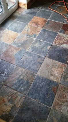 a tile floor in a kitchen with a window and an orange cord plugged into it