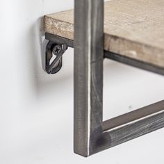 a close up of a metal object on a white wall near a wooden chair and shelf