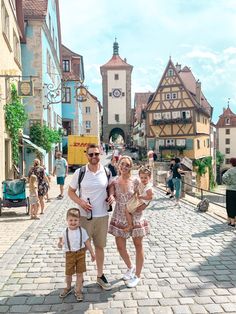 a man, woman and child are standing in the middle of a cobblestone street