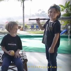 two young boys standing next to each other on a bench in front of a swimming pool