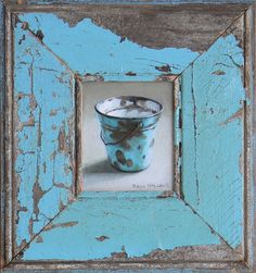 an old blue frame with a cup in it