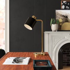 a desk lamp sitting on top of a wooden table in front of a fire place