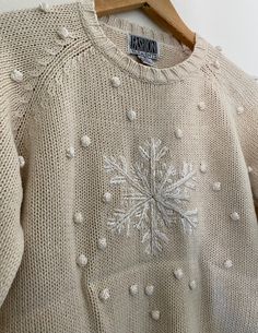 a sweater with snowflakes is hanging on a wooden hanger