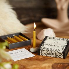 a candle on a table next to some cards and a box of matches in front of a woman's face