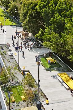 an aerial view of people walking and sitting on benches in a park next to trees