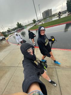 three people in hoodies are playing hockey on the street with one person holding a stick