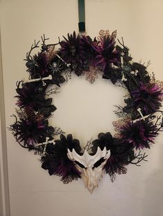 a wreath with purple flowers and an animal's skull