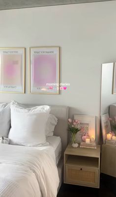 a white bed sitting next to two framed pictures