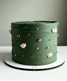 a green cake sitting on top of a white plate covered in icing and flowers