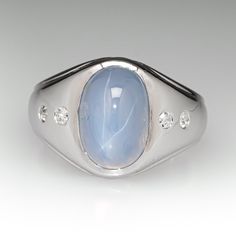 an oval shaped ring with a blue stone surrounded by white diamonds on a gray background