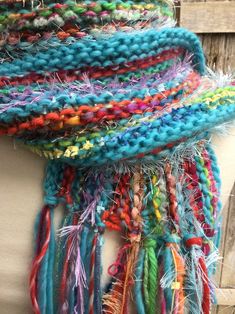 a woman wearing a multicolored knitted scarf with fringes on her neck