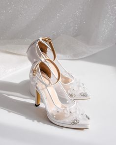 a pair of white high heeled shoes sitting on top of a white cloth covered floor