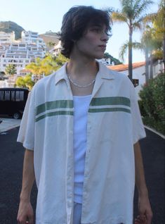 a man standing in the street with his hand on his hip and wearing a white shirt