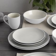 a table set with plates, cups and saucers on top of a place mat