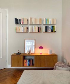 a bed room with a neatly made bed and bookshelves on the wall above it