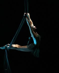 a woman hanging upside down on a rope in the dark with her legs spread out