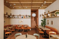 the interior of a restaurant with wooden tables and orange chairs, potted plants on the wall