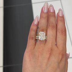 a woman's hand with two wedding rings on her left and the other hand holding an engagement ring