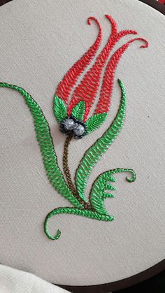 a close up of a embroidery design on a white piece of cloth with red and green flowers