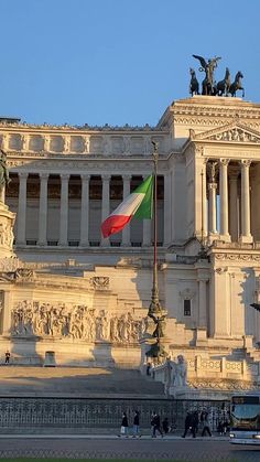 an italian flag flying in front of a building with statues on the sides and columns