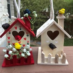 two small bird houses with birds on them