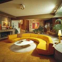 a living room filled with yellow furniture and a fire place in the middle of it