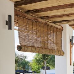 an outdoor covered patio area with wooden blinds and furniture on the outside, near a swimming pool