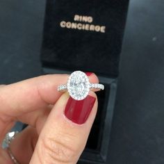 a woman's hand holding a diamond ring in front of a black velvet box