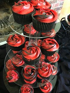 cupcakes with red frosting are stacked on top of each other in front of a fireplace